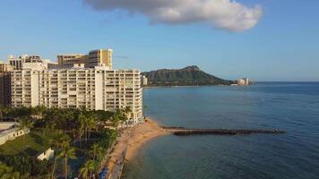 Aerial view Honolulu skyline with oceanfront resorts, Fort DeRussy Beach with golden sand, palm trees, and Diamond Head mountain in the background video
