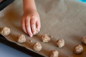 View of children's hands make nut cookies and place them on a baking sheet photo