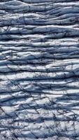 Aerial View reveals the intricate patterns of deep crevasses and textured ice on a Svinafellsjokull Glacier in Iceland. Vertical footage video