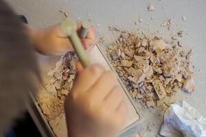 Top view of a child with the help of a geologist's kit extracts a jasper in a plaster cast photo