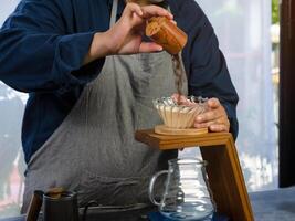 Coffee drip maker. Barista pouring ground coffee in paper filter photo