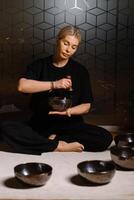 Practitioner uses singing bowls for meditation in a serene studio environment during a mindful evening session photo