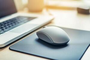 Computer Mouse on Black Mouse Pad with Laptop in Bright Office Environment photo