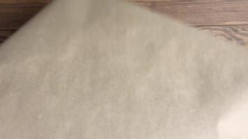 Women's hands unfold roll of craft paper and place it on wooden table. Sheet of wrapping paper for creativity. video