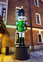 Oversized nutcracker statues in green and yellow stand in front of a historic brick building, adding a festive holiday charm to the courtyard. The figures, inspired by traditional wooden nutcrackers photo