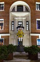 Oversized nutcracker statues in green and yellow stand in front of a historic brick building, adding a festive holiday charm to the courtyard. The figures, inspired by traditional wooden nutcrackers photo