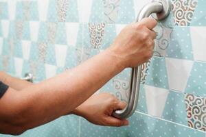 Asian woman patient use toilet support rail in bathroom, handrail safety grab bar, security in nursing photo