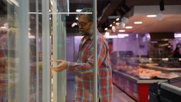 Senior man selecting eggs from refrigerated section in store video