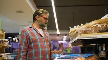 Senior man buying bread at grocery store bakery section video