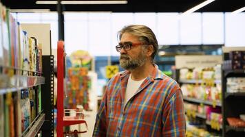 Senior man buying shampoo on sale in a supermarket video