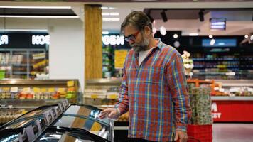 Senior man selecting frozen red fish salmon at grocery store video