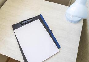 Shot of the plastic folder on the desk with paper clip holder on the top. A4 size paper mock up. Stationary photo