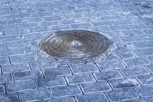 Manhole and interlock bricks with frost on them. Texture photo