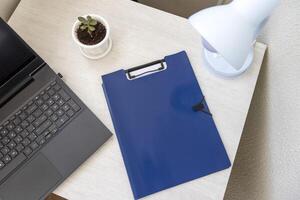 Shot of the plastic documents folder on the office desk with paper clip holder on the top and other office items. A4 size paper mock up. Stationary photo