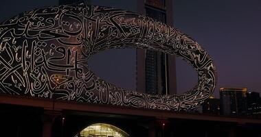 Museum of the Future with glowing hieroglyphs among the glass skyscrapers of Dubai at dusk, view from the window of a moving car video
