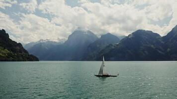 A sailboat in the middle of a lake with mountains in the background video