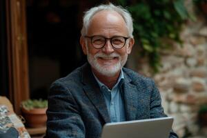 Senior man smiling while working on laptop in cozy indoor setting with natural light photo