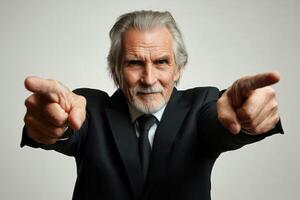 Elderly man in formal attire pointing at the camera with a confident expression indoors photo