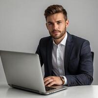 A man in a suit is sitting at a desk with a laptop photo