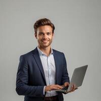 Smiling businessman holding laptop over gray background photo