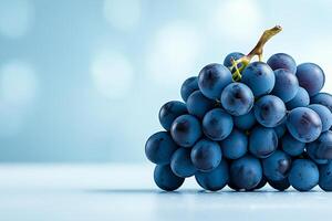 Fresh blue grapes stacked on light blue background, creating vibrant and appealing display. soft focus adds dreamy quality to image, enhancing its visual charm photo