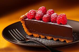 rich chocolate tart slice topped with fresh raspberries, served on black plate. dessert features crumbly crust and glossy filling, perfect for indulgence photo