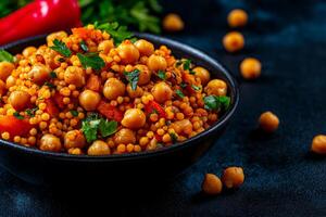 vibrant bowl of couscous salad featuring chickpeas, bell peppers, and fresh herbs, perfect for healthy meal. colorful ingredients create appetizing and nutritious dish photo