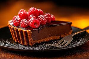 delicious chocolate tart topped with fresh raspberries, served on black plate. rich filling contrasts beautifully with sweet berries, creating inviting dessert photo