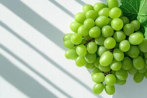 Fresh green grapes with shadows on white background create vibrant and refreshing scene. natural light enhances grapes color and texture, making them visually appealing photo