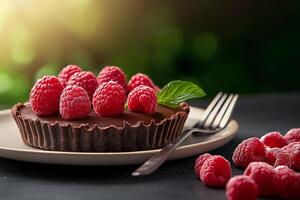 simple round chocolate tart topped with fresh raspberries and mint leaf, served on plate with fork. vibrant colors and textures create inviting dessert scene photo