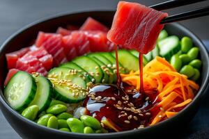 fresh and vibrant sashimi bowl featuring tuna, avocado, cucumber, and colorful vegetables, drizzled with sauce and garnished with sesame seeds, perfect for healthy meal photo
