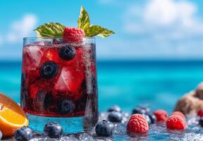 Colorful summer cocktail with blueberries, raspberries, and mint, served in glass. Refreshing drink against vibrant ocean backdrop, perfect for warm days photo
