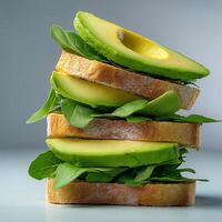 Fresh whole grain bread stacked with avocado slices and leafy greens, creating healthy and vibrant sandwich Perfect for nutritious meal or snack photo