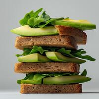 stack of sliced brown bread layered with fresh avocado and leafy greens, showcasing healthy and vibrant meal option. This visually appealing sandwich highlights nutritious ingredients photo