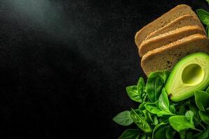 Fresh avocado and whole grain bread on dark background with greens photo