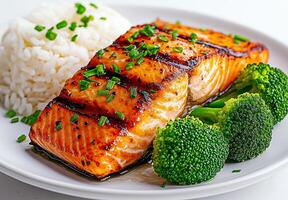 Grilled salmon fillet served with broccoli and long grain rice, garnished with chives, offers delicious and healthy meal option. vibrant colors and textures create appetizing presentation photo