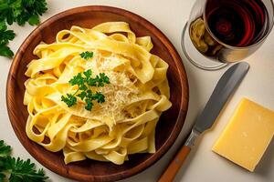 Delicious fettuccine pasta topped with creamy sauce, garnished with parsley, served with glass of red wine and cheese. perfect meal for pasta lovers photo