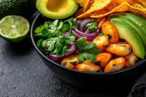Delicious ceviche bowl with shrimp, avocado, lime, and tortilla chips, garnished with fresh cilantro and red onion, perfect for refreshing meal photo
