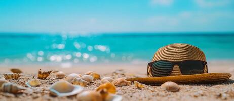 straw hat and sunglasses resting on sandy beach with seashells, evoking relaxing summer vibe. turquoise water sparkles in background, creating serene atmosphere photo