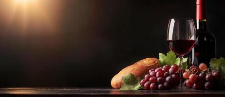 still life featuring glass of red wine, bottle of wine, fresh grapes, and loaf of bread on dark table, evoking warm and inviting atmosphere photo