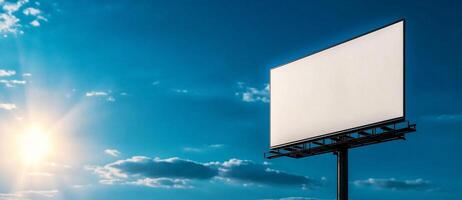 white blank billboard stands against bright blue sky, illuminated by sunlight, creating perfect canvas for advertising or messages photo