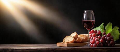 still life featuring glass of red wine, fresh grapes, and sliced bread on wooden table, illuminated by soft light, creating warm and inviting atmosphere photo