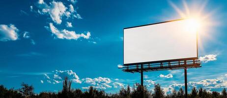 large white blank billboard stands against bright blue sky, illuminated by sunlight. scene captures serene outdoor setting with scattered clouds and greenery photo