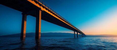large modern bridge spanning over sea at sunset, showcasing its architectural beauty and reflection in water. serene atmosphere evokes sense of tranquility photo