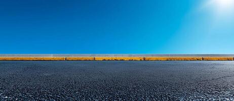 clear blue sky above smooth asphalt road with concrete curb. scene conveys sense of openness and tranquility, perfect for backgrounds or design projects photo