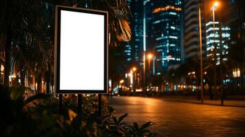 empty white billboard stands in city center at night, surrounded by palm trees and illuminated buildings. scene conveys sense of urban tranquility and potential photo