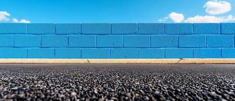 Bright blue concrete wall against clear sky, with asphalt floor. vibrant colors create striking contrast, evoking sense of openness and tranquility photo