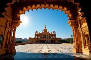 stunning view of Indian palace courtyard framed by intricate architecture, showcasing vibrant colors and clear blue sky. sunlight enhances beauty of structure photo