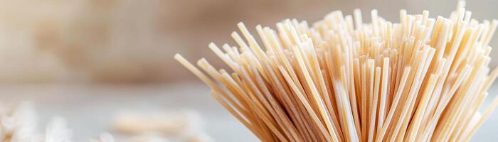 Golden spaghetti strands are captured in a close-up view, showcasing their gourmet texture against a softly blurred warm background, perfect for culinary branding photo