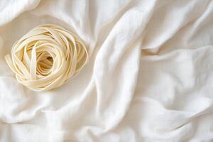 A handmade pasta nest is elegantly twirled on soft linen fabric, showcasing neutral earthy tones. The airy and fresh composition allows ample space for text, highlighted by cinematic lighting photo